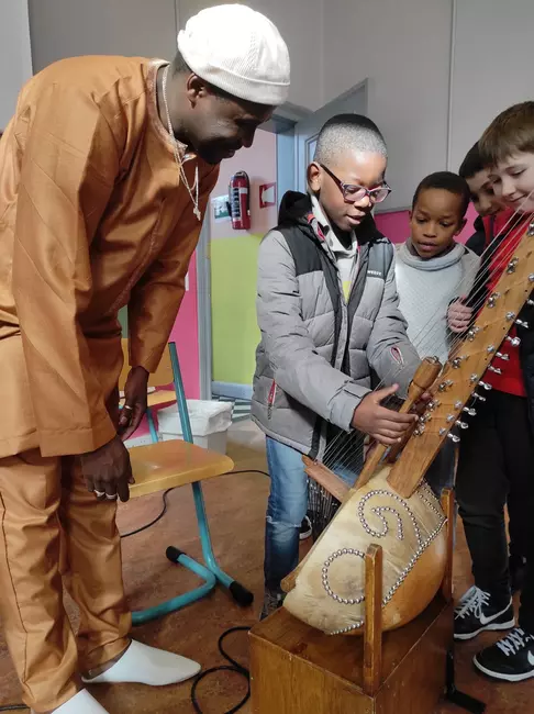 un musicien fait jouer les élèves sur un instrument